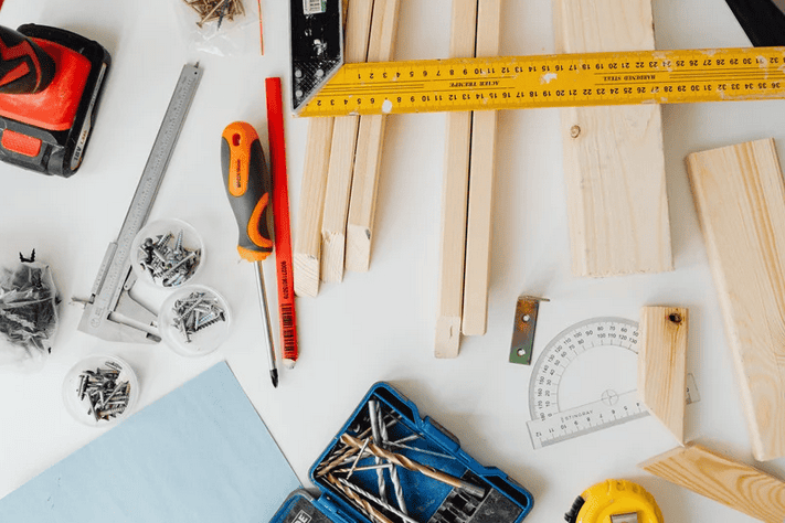 Essential tools for new homeowners including a drill, level, and stud finder laid out for a DIY project